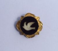 A small circular brooch decorated with a dove. App