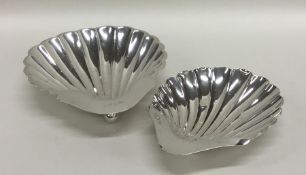 A matched pair of silver shell shaped dishes on ba