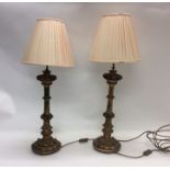 A pair of gilt bedside lamps with pink shades. Est
