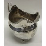 A Georgian silver cream jug with reeded rim on bal
