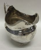 A Georgian silver cream jug with reeded rim on bal