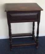 An oak hinged top side table with stretcher base.