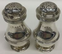 A pair of baluster shaped silver peppers with lift