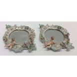 A pair of decorative cherub mounted mirrors decora