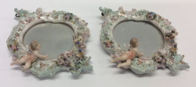 A pair of decorative cherub mounted mirrors decora