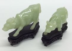 A graduated pair of carved hard stone oxen on wood