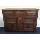 An oak three drawer sideboard with carved doors. E