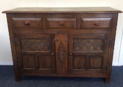 An oak three drawer sideboard with carved doors. E