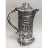 A tall flamboyant silver beer jug embossed with fl