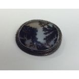 A moss agate and silver oval brooch in pierced fra