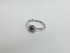 A pretty emerald and diamond cluster ring in 18 ca