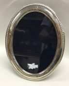 A large oval silver picture frame. London. By RC.