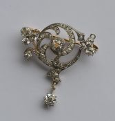 A large diamond brooch in the form of a scroll wit