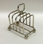 A silver four division toast rack on ball feet. Bi