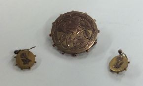 A small gold circular brooch along with matching e