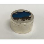 A circular silver counter box decorated with blue