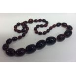 A graduated string of tapering red beads with conc