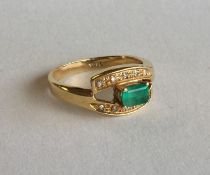 An emerald and diamond eleven stone crossover ring