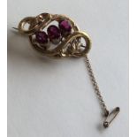 A pinch-back three stone brooch with scroll decora