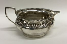 A heavy half fluted silver cream jug with gadroon