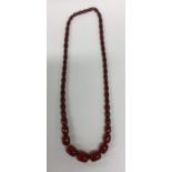 A graduated string of red amber type beads. Approx