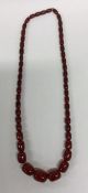 A graduated string of red amber type beads. Approx