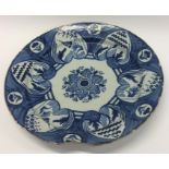 An Antique pottery charger decorated in blue and w