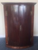 An Antique mahogany bow front corner cupboard with