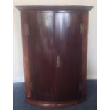 An Antique mahogany bow front corner cupboard with