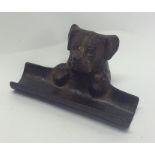 A cast pen tray in the form of a dog with textured