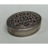 An oval silver box attractively decorated with scr