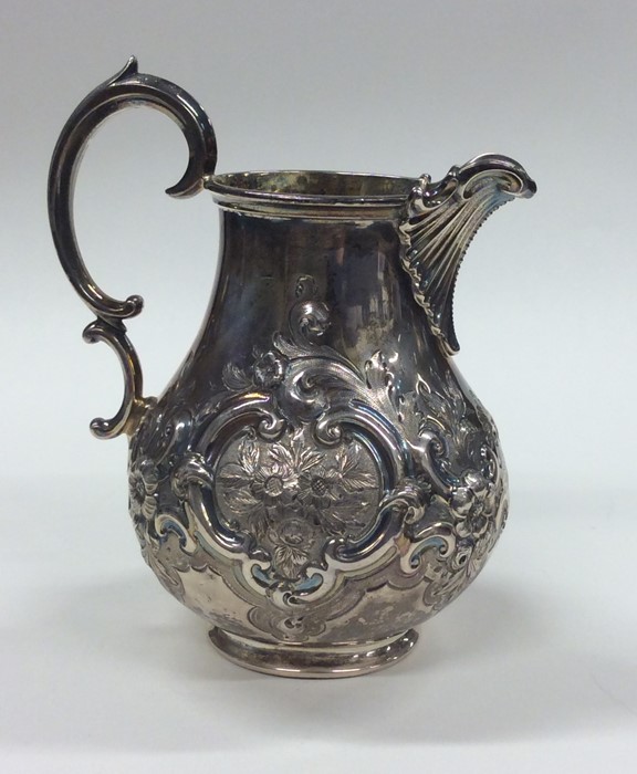 A good Victorian embossed silver cream jug decorat