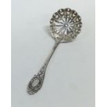 A small silver sifter spoon decorated with scrolls