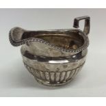 A heavy Georgian silver half fluted cream jug with