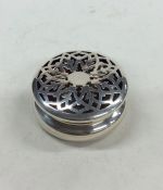 A small circular silver box with pierced decoratio