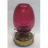 A large cranberry glass lamp on brass reservoir. E