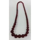 A graduated string of red amber type beads. Approx