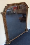 A gilt framed wall mirror with shaped top to carve