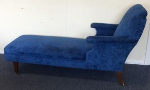 A blue upholstered day bed on tapering supports. E