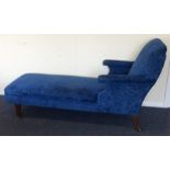 A blue upholstered day bed on tapering supports. E