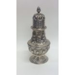 A large embossed silver sugar caster decorated wit
