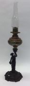 A tall porcelain mounted oil lamp on cast iron bas