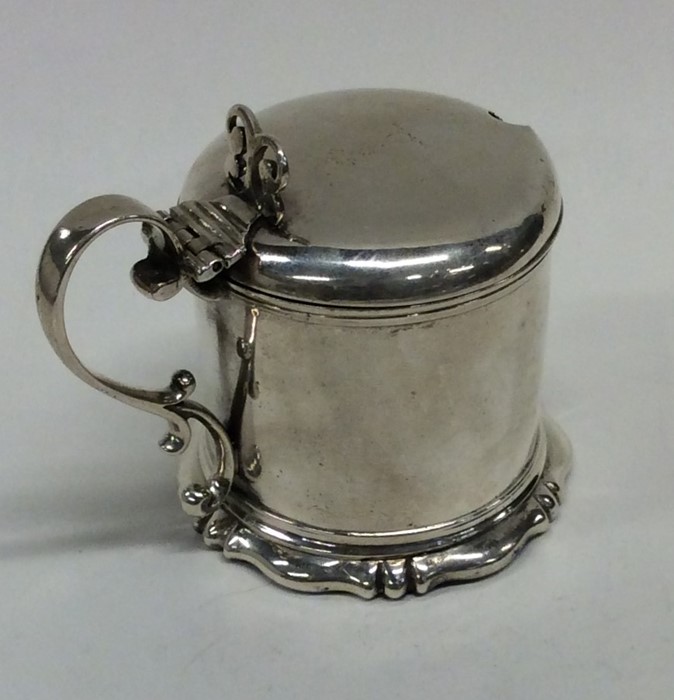 A Victorian hinged top mustard pot on scroll base.