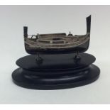 A small silver model of a boat mounted on oval woo