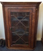 A small oak corner cupboard with bevelled glass. E