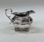 An Edwardian silver cream jug with floral decorati