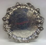 A heavy silver salver decorated with scrolls and f