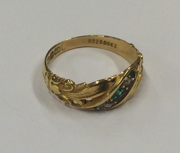 An emerald and diamond ring with scroll decoration