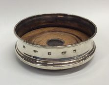 A modern silver wine coaster on mahogany panelled
