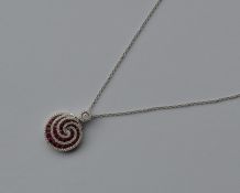 A stylish ruby and diamond swirl pendant with loop